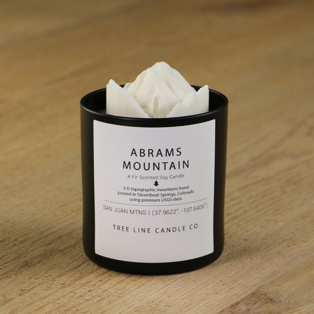 A white soy wax candle replica of Abrams Mountain in a round, black glass.