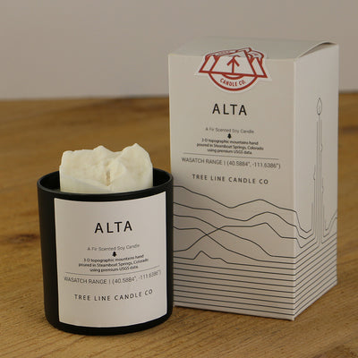 A white wax candle named Alta summit is next to a white box with red and black lettering.