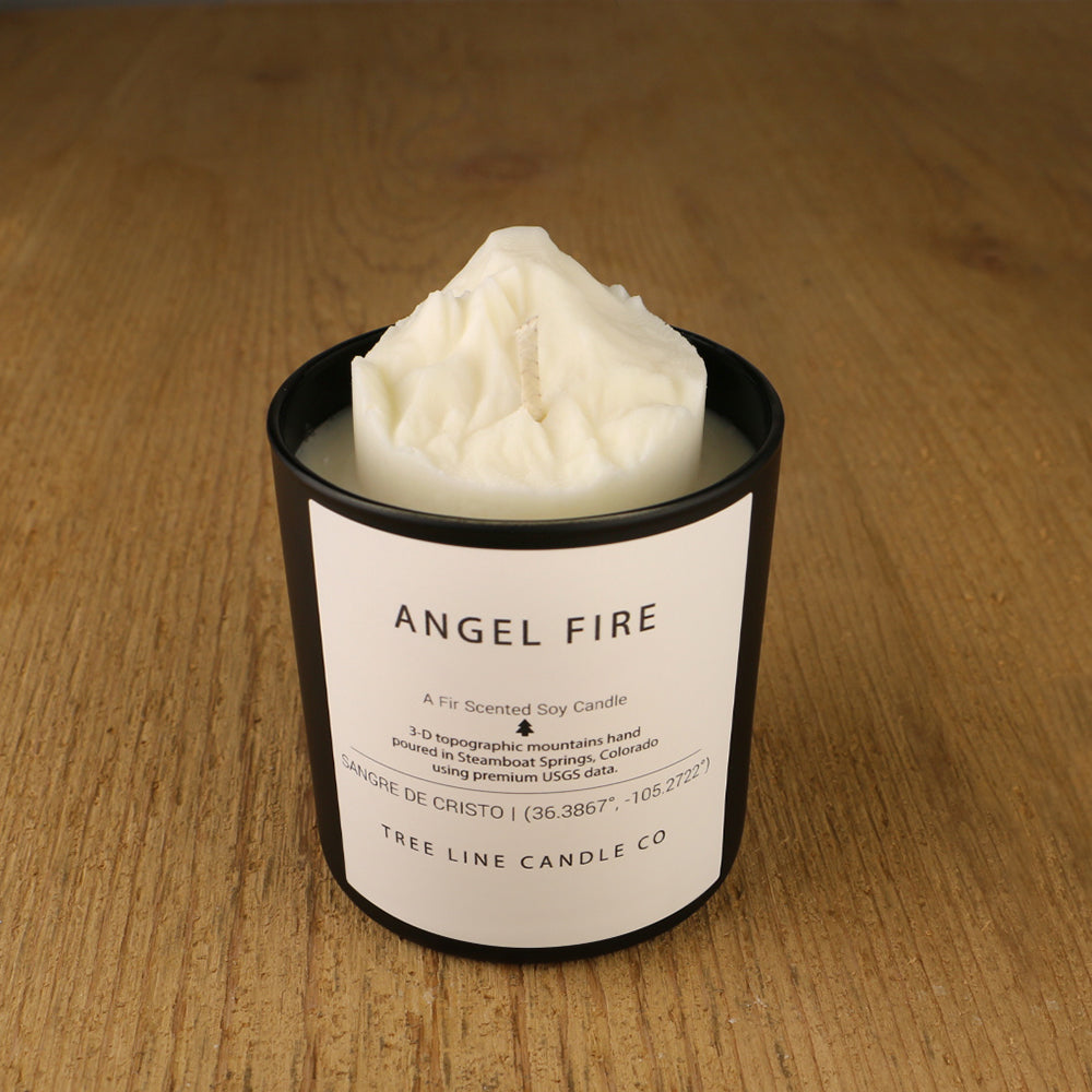 A white soy wax replica candle of Angel Fire in a round, black glass.