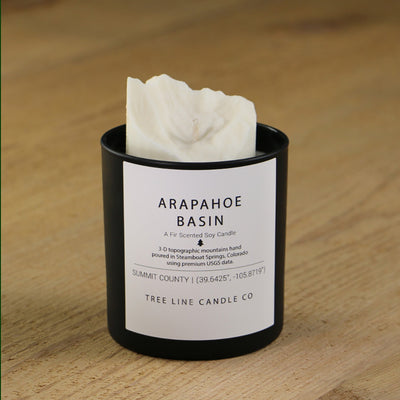  A white soy wax replica candle of  Arapahoe Basin in a round, black glass.