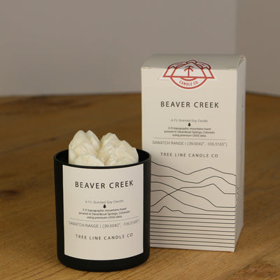 A white wax candle named Beaver Creek is next to a white box with red and black lettering.