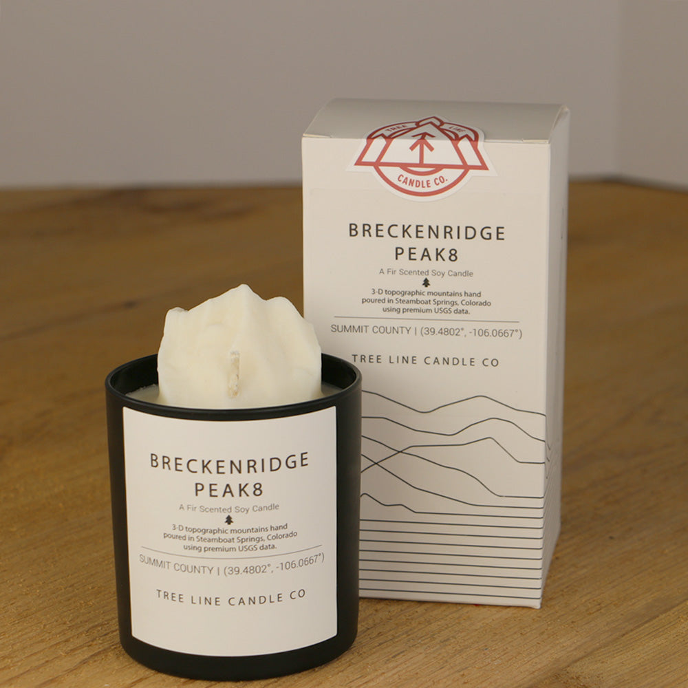 A white wax candle named Breckenridge Peak 8 is next to a white box with red and black lettering.