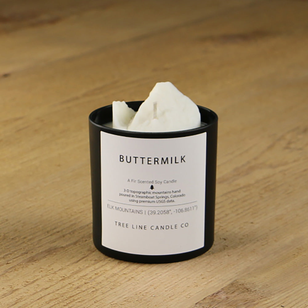  A white soy wax replica candle of Buttermilk summit in a round, black glass.