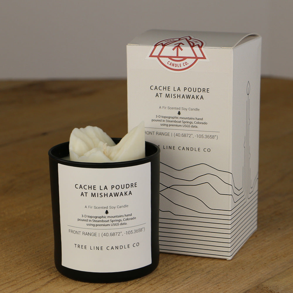 A white wax candle named Cache La Poudre is next to a white box with red and black lettering.