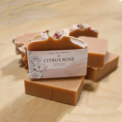 A bar of Citrus Rose soap sits atop another bar of soap with several laying in the background.