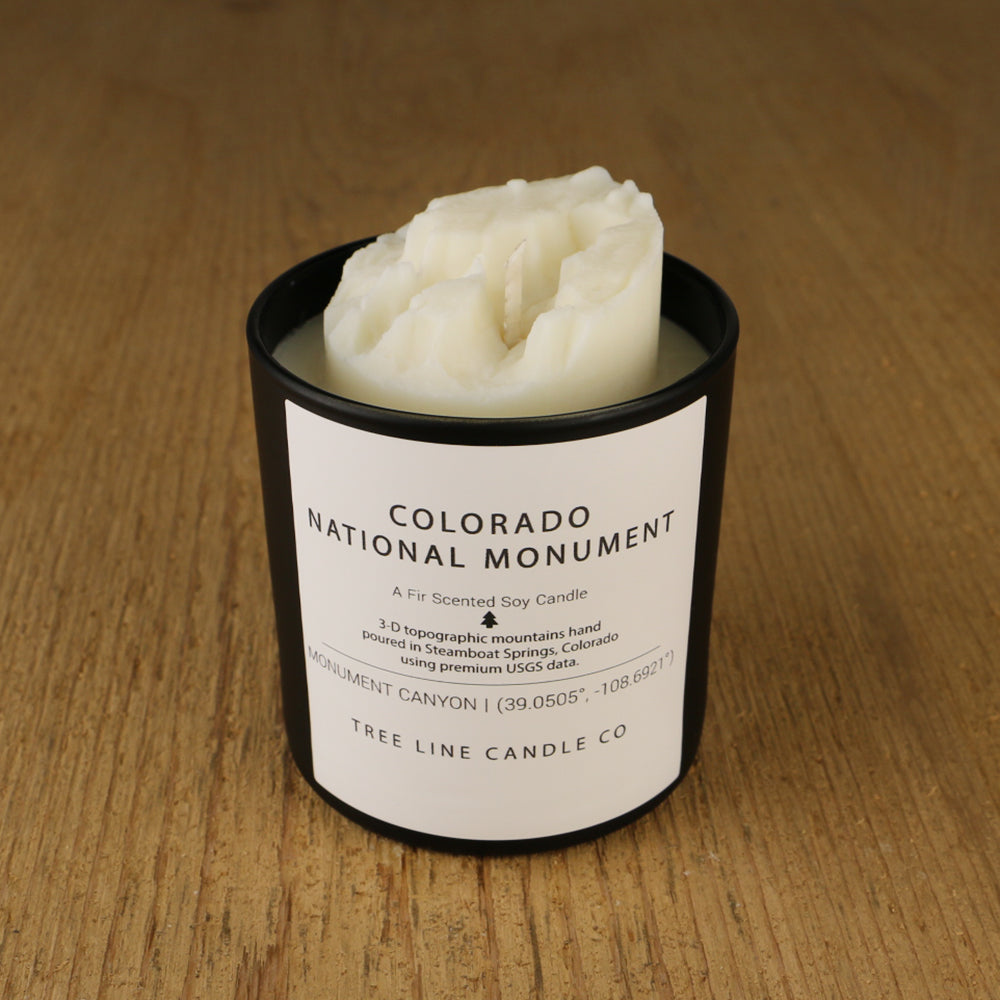 A white soy wax replica candle of Colorado National Monument in a round, black glass.