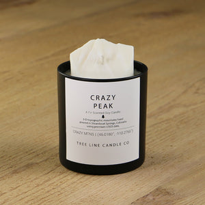  A white soy wax replica candle of Crazy Peak in a round, black glass.