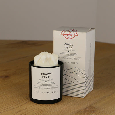 A white wax candle named Crazy Peak is next to a white box with red and black lettering.