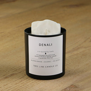  A white soy wax replica candle of Denali mountain in a round, black glass.