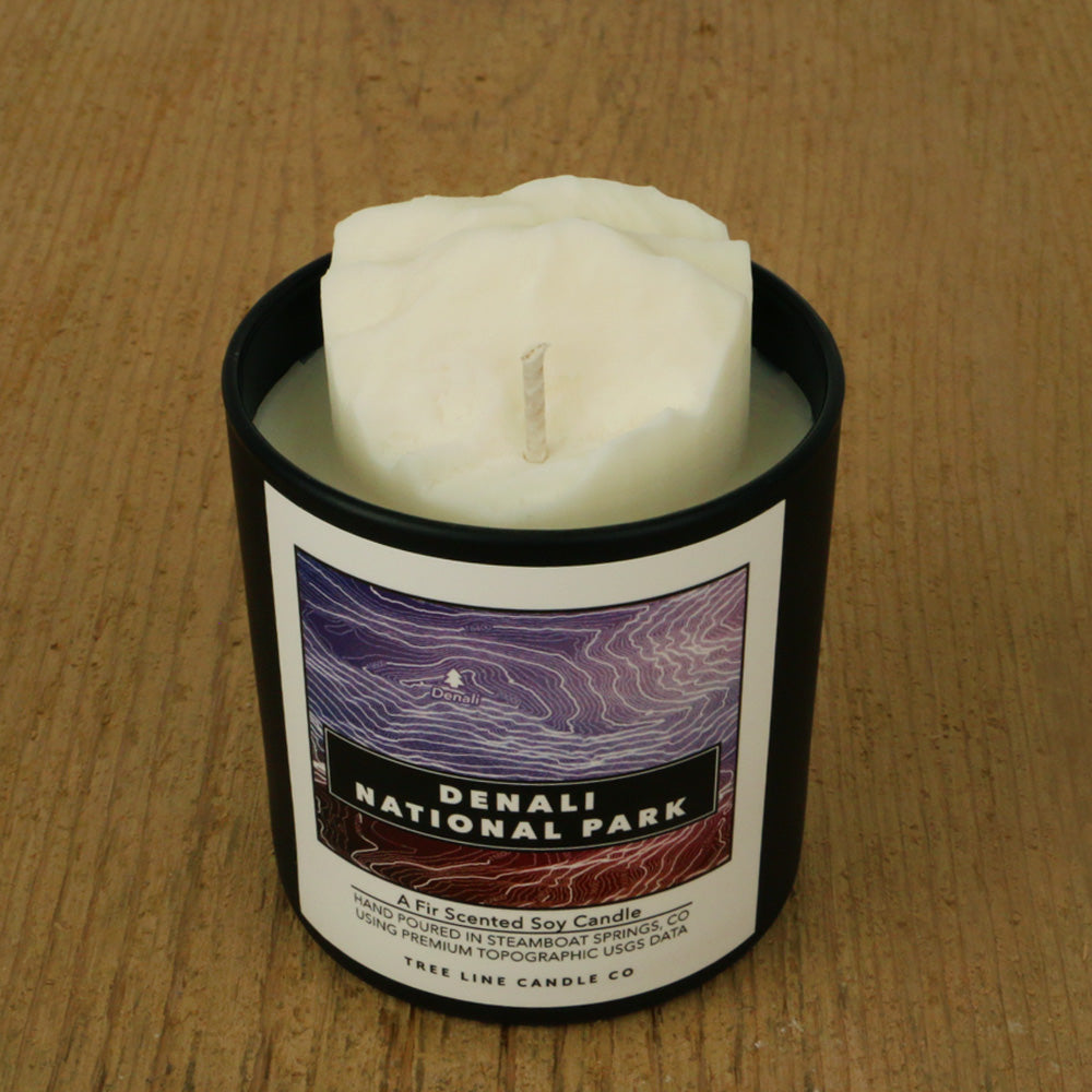  A white soy wax replica candle of Denali in a round, black glass.