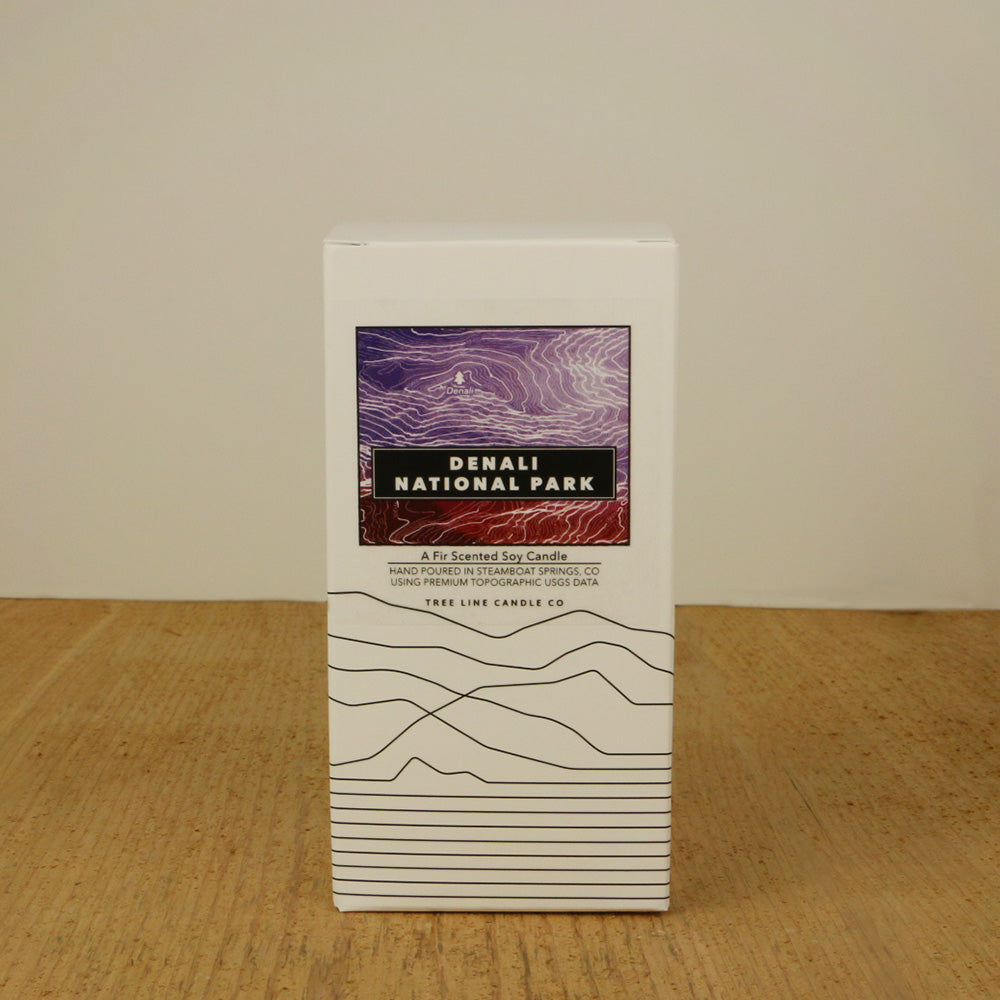 A white box with a purple and maroon label with topography lines by Tree Line Candle Co.