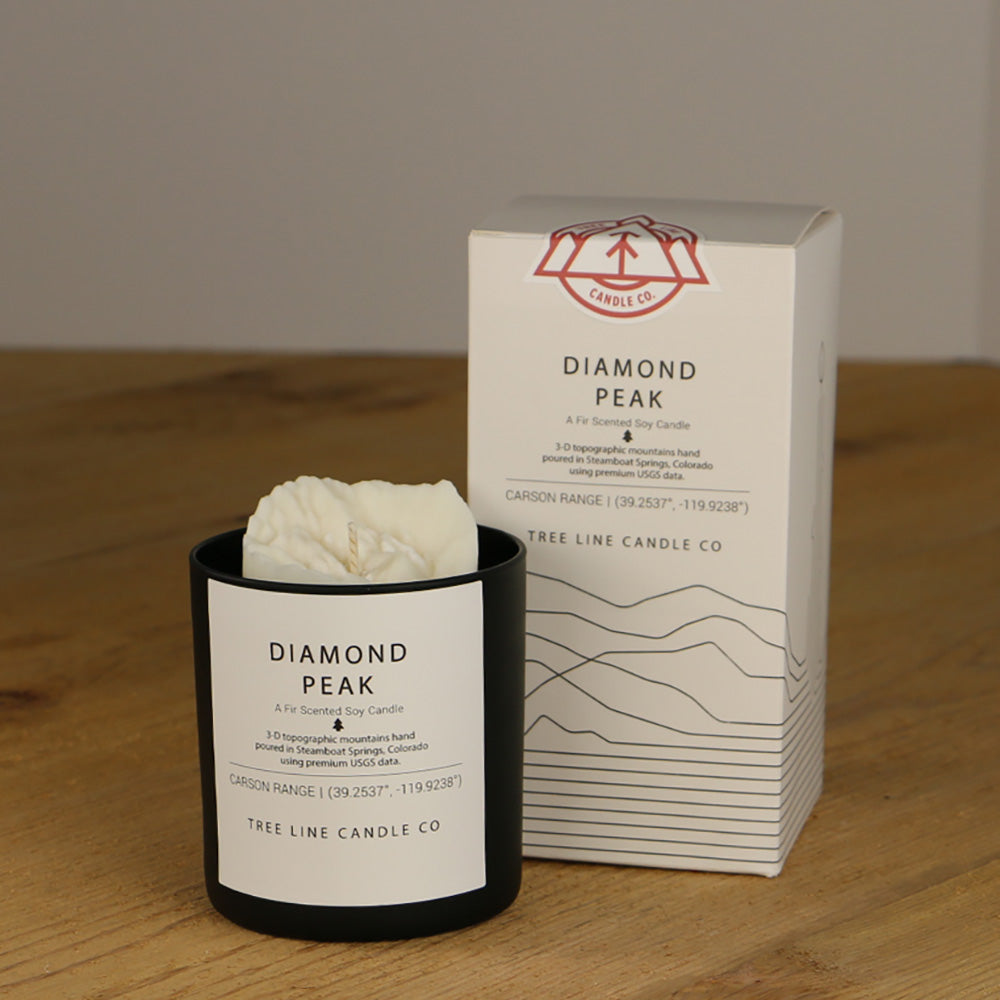 A white wax candle named Diamond Peak is next to a white box with red and black lettering.