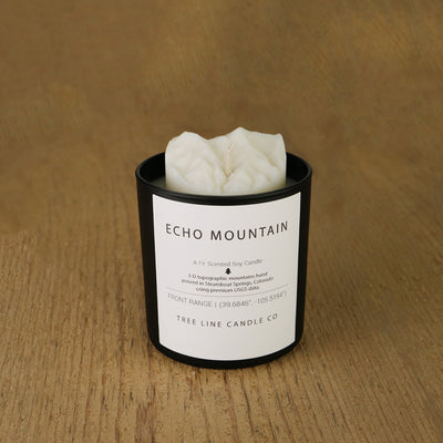 A white soy wax replica candle of Echo Mountain in a round, black glass.