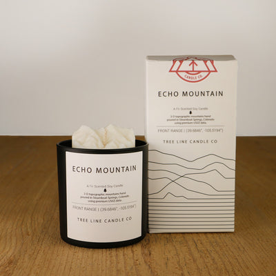 A white wax candle named  Echo Mountain is next to a white box with red and black lettering.