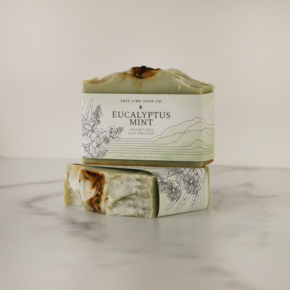 A bar of Eucalyptus Mint soap sits atop another bar of soap with the same fragrance.