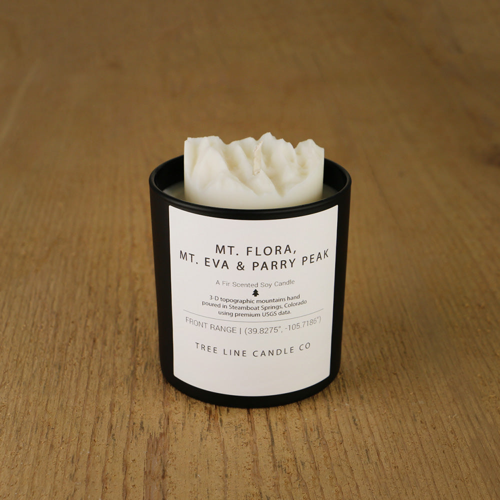 A white soy wax replica candle of Mt. Flora, Mt. Eva & Parry Peak in a round, black glass.