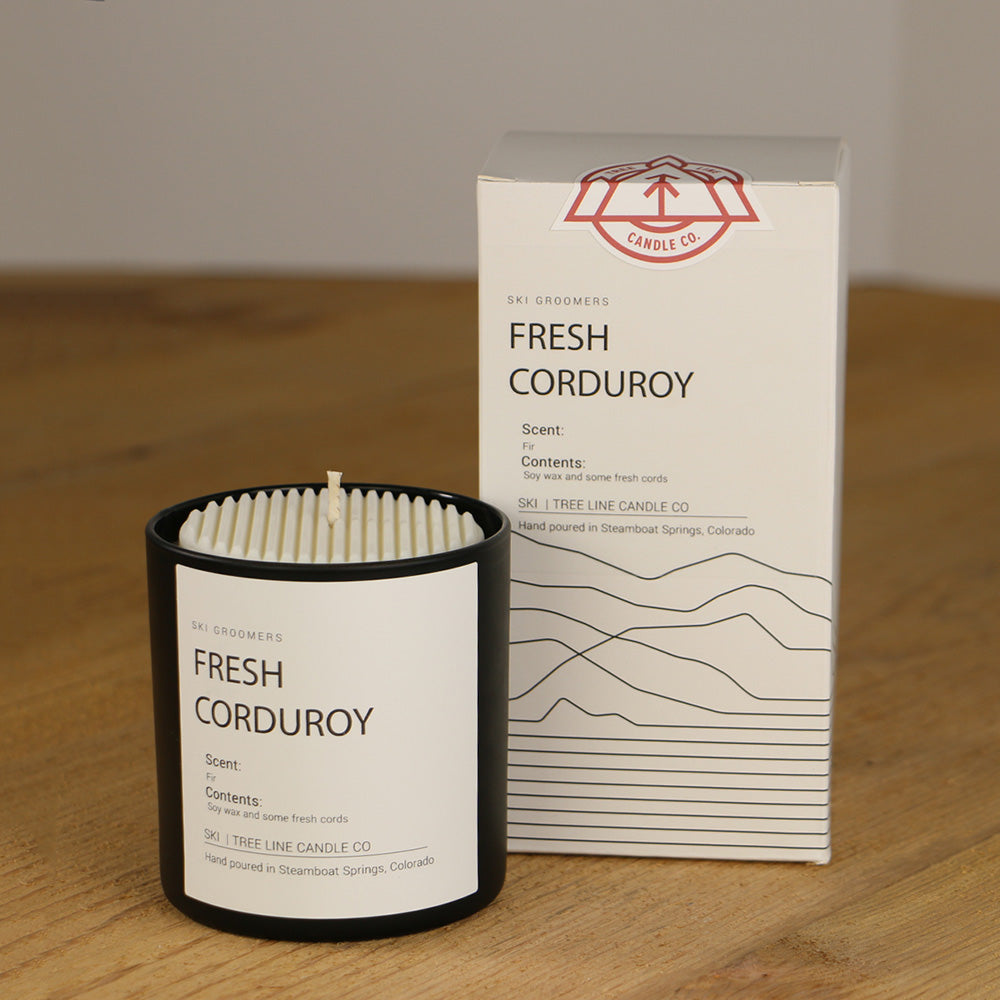 A white wax candle named Fresh Corduroy is next to a white box with red and black lettering.