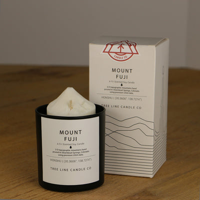 A white wax candle named Mount Fuji is next to a white box with red and black lettering.