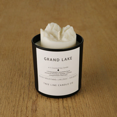 A white soy wax replica candle of Grand Lake in a round, black glass.