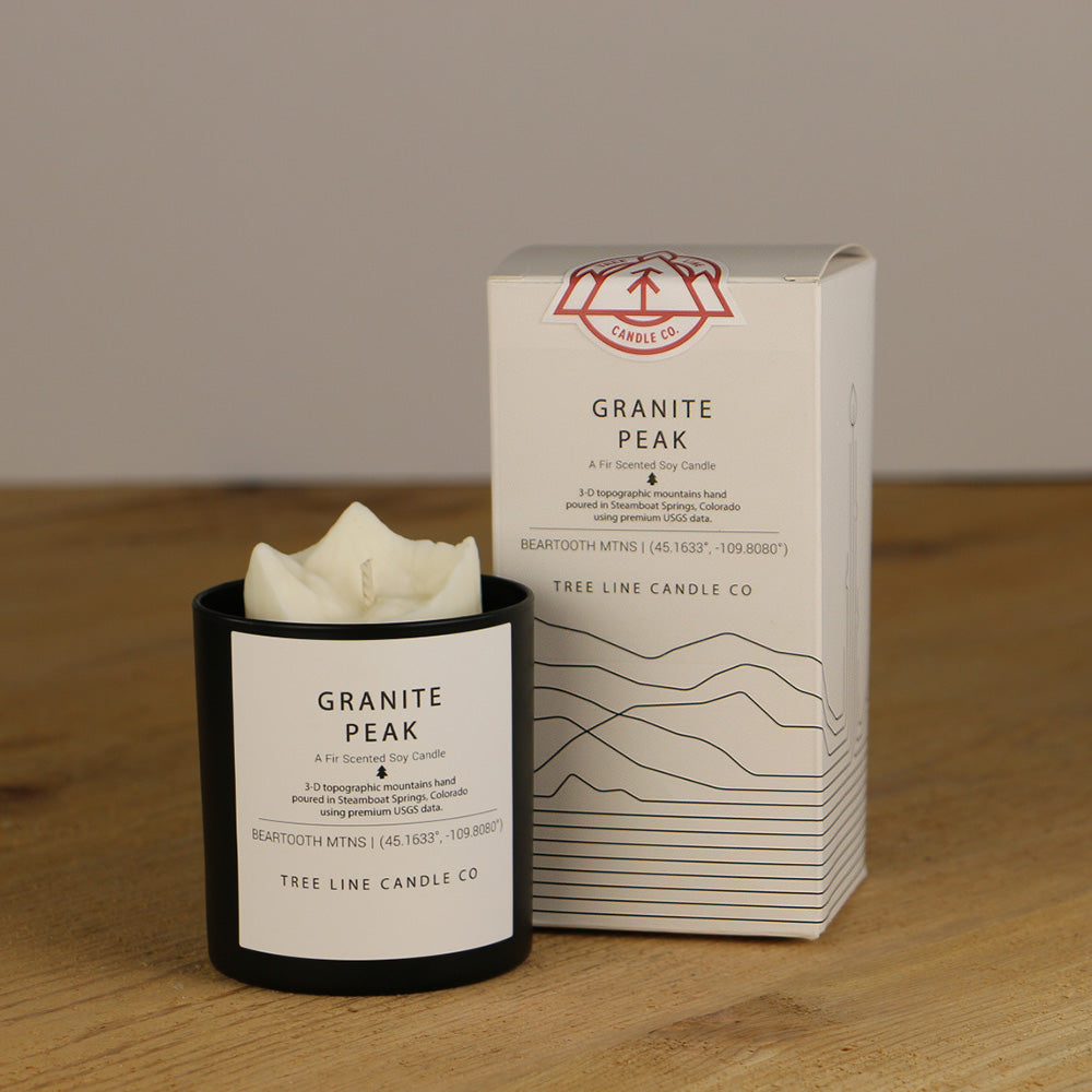 A white wax candle named Granite Peak is next to a white box with red and black lettering.