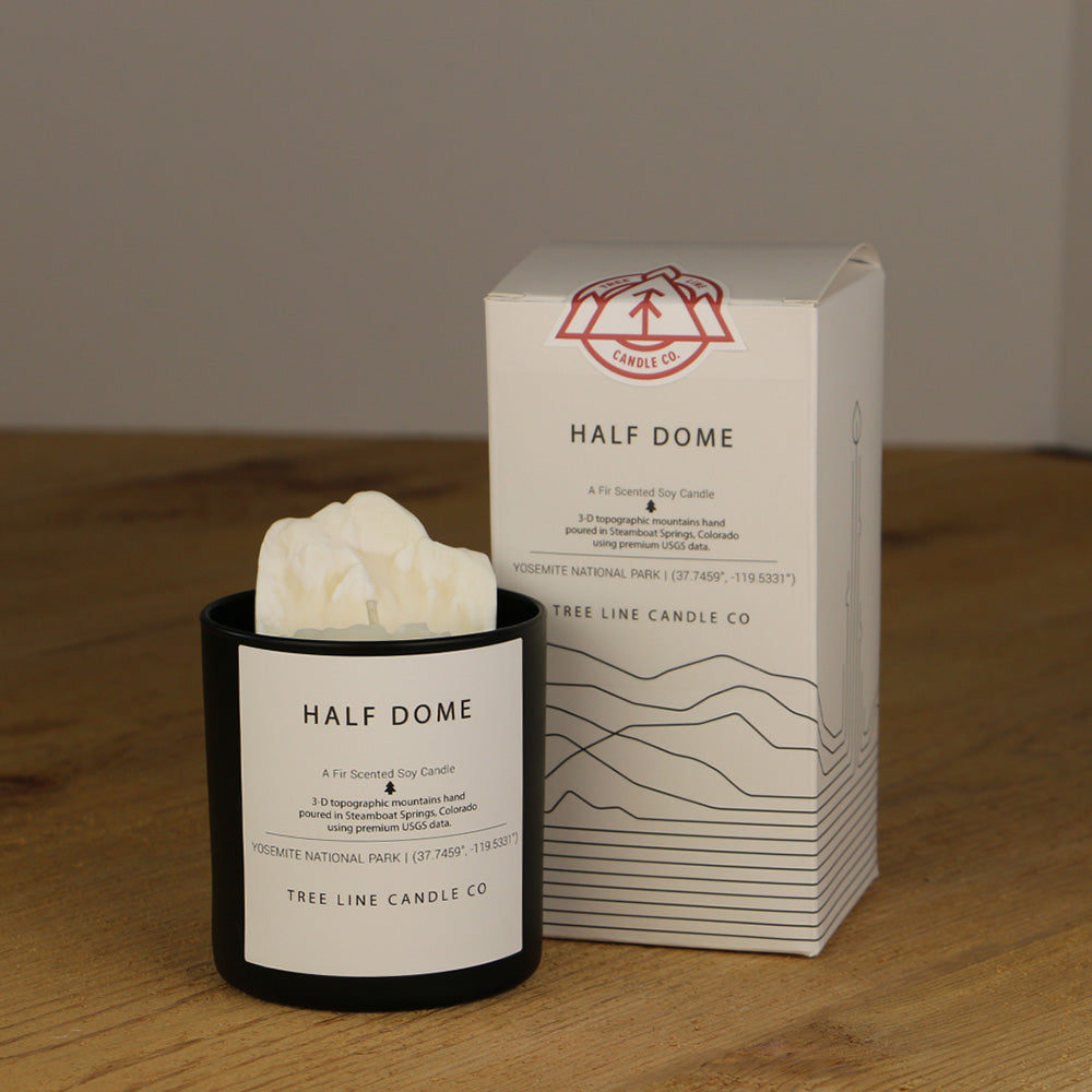 A white wax candle named Half Dome is next to a white box with red and black lettering.