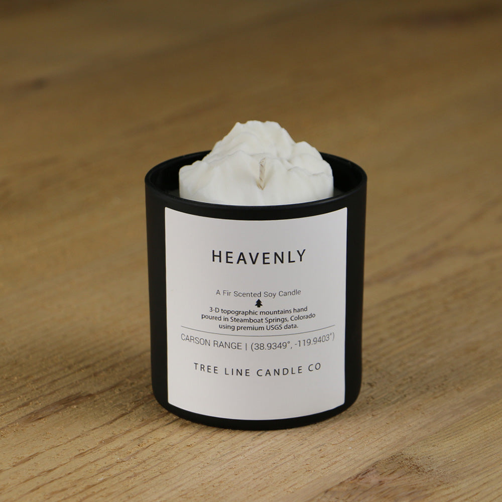 A white soy wax replica candle of  Heavenly mountain in a round, black glass.