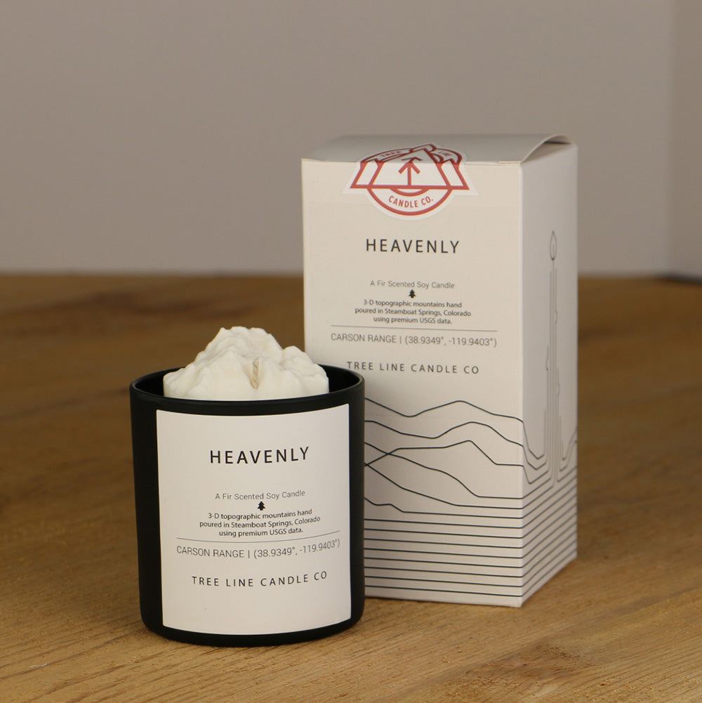 A white wax candle named Heavenly summit is next to a white box with red and black lettering.