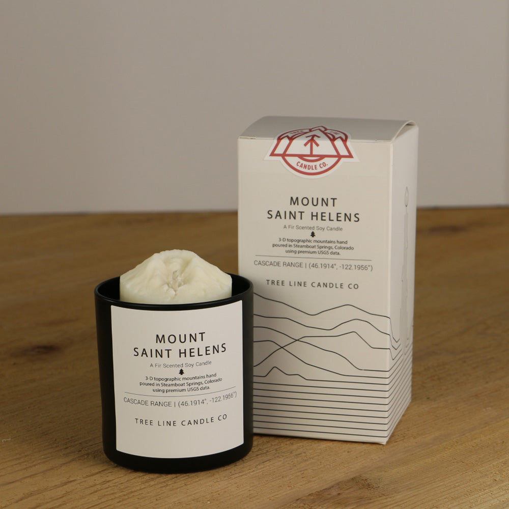 A white wax candle named Mount Saint Helens is next to a white box with red and black lettering.