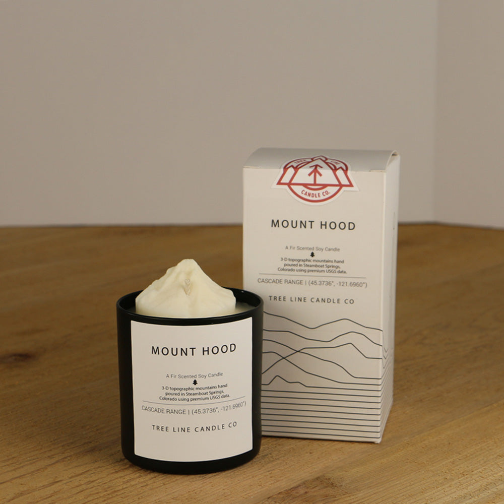 A white wax candle named Mount Hood is next to a white box with red and black lettering.
