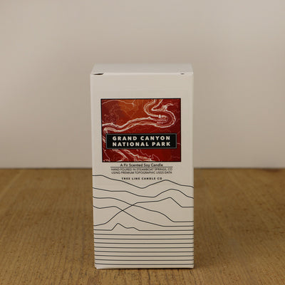 A white box with an orange and red label with topography lines by Tree Line Candle Co.