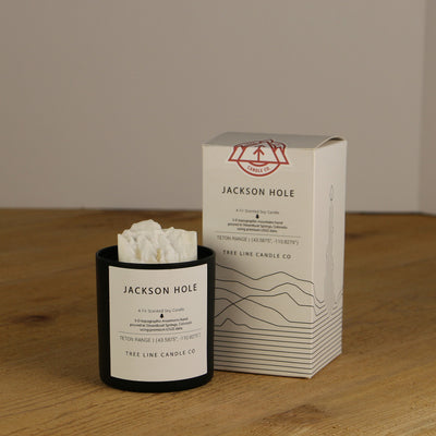 A white wax candle named Jackson Hole is next to a white box with red and black lettering.