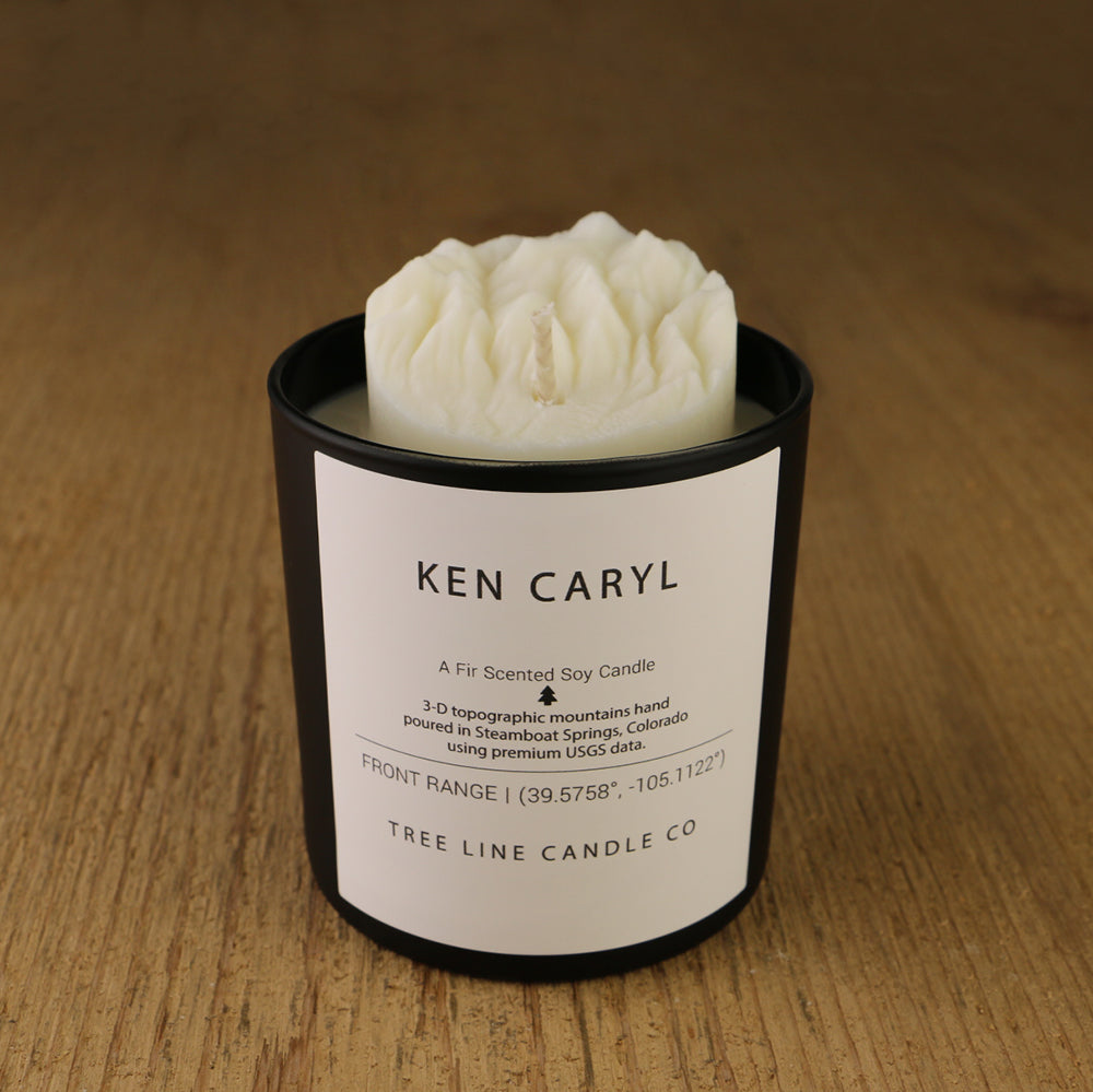 A white soy wax replica candle of Ken Caryl in a round, black glass.