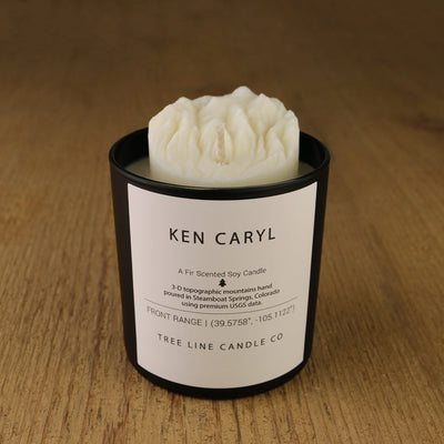 A white soy wax replica candle of Ken Caryl in a round, black glass.