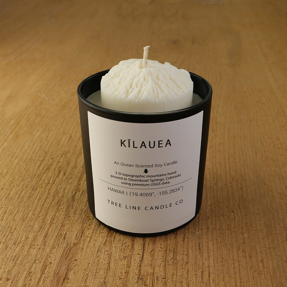 A white soy wax replica candle of Kïlauea in a round, black glass.