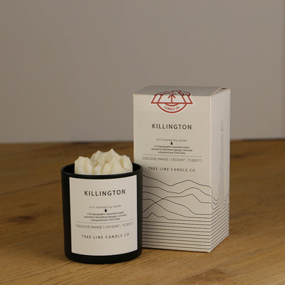 A white wax candle named Killington is next to a white box with red and black lettering.