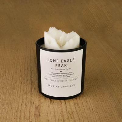 A white soy wax replica candle of Lone Eagle Peak in a round, black glass.