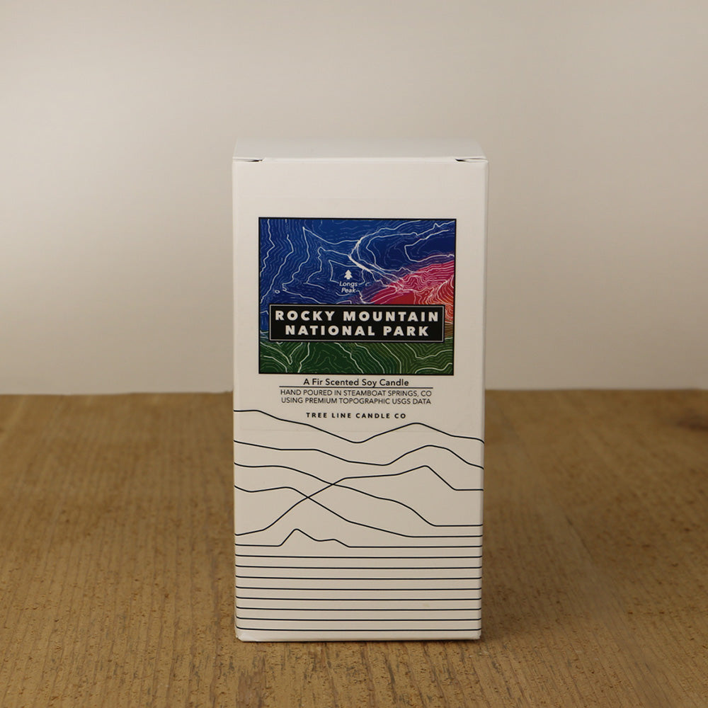 A white box with a blue, red-orange and green label with topography lines by Tree Line Candle Co.