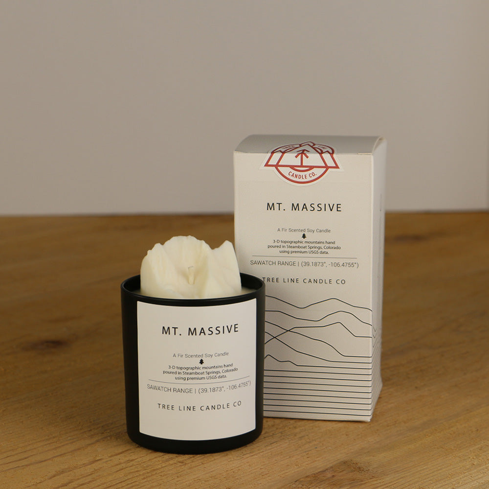 A white wax candle named Mt. Massive is next to a white box with red and black lettering.