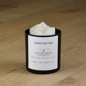  A white soy wax replica candle of Northstar in a round, black glass.