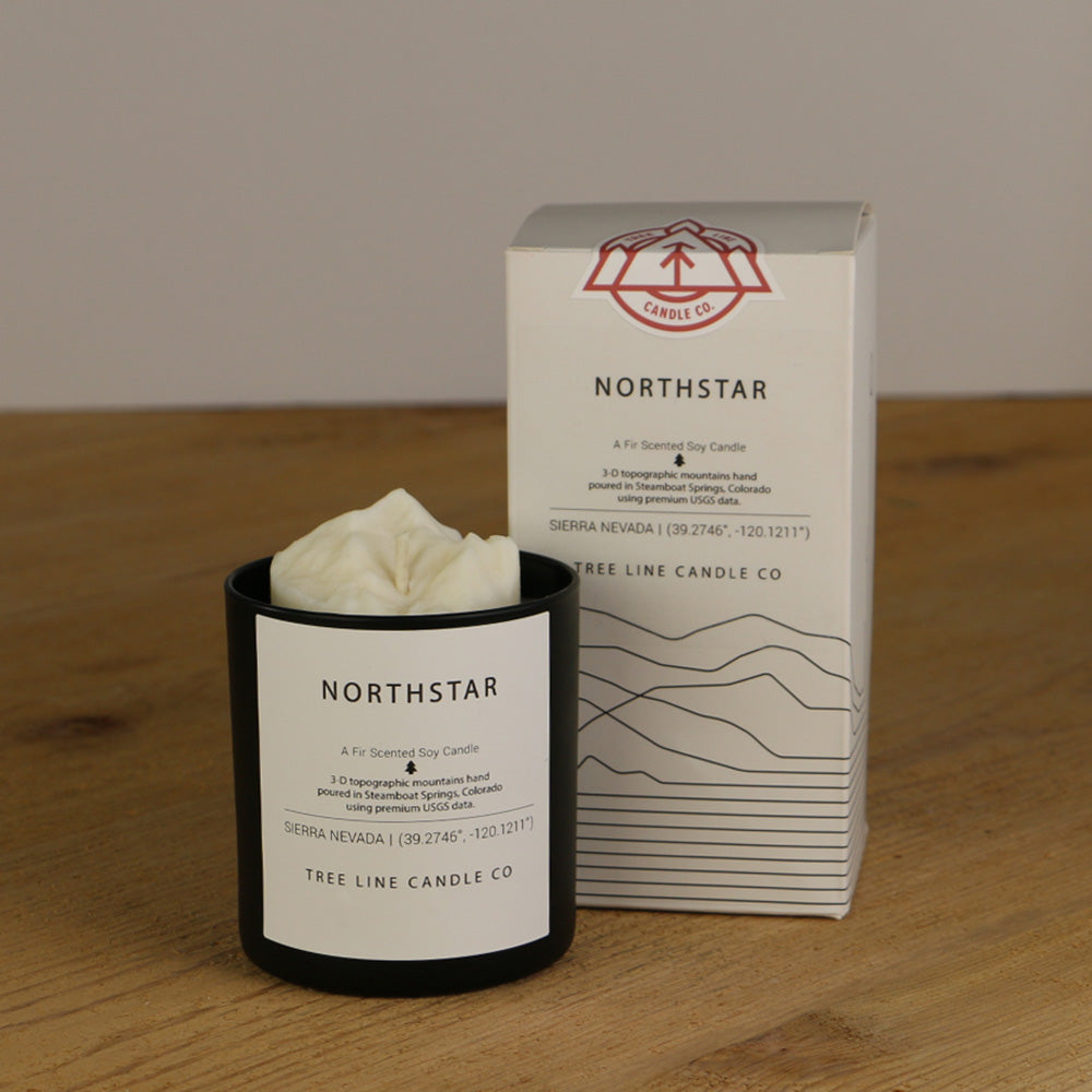 A white wax candle named Northstar is next to a white box with red and black lettering.