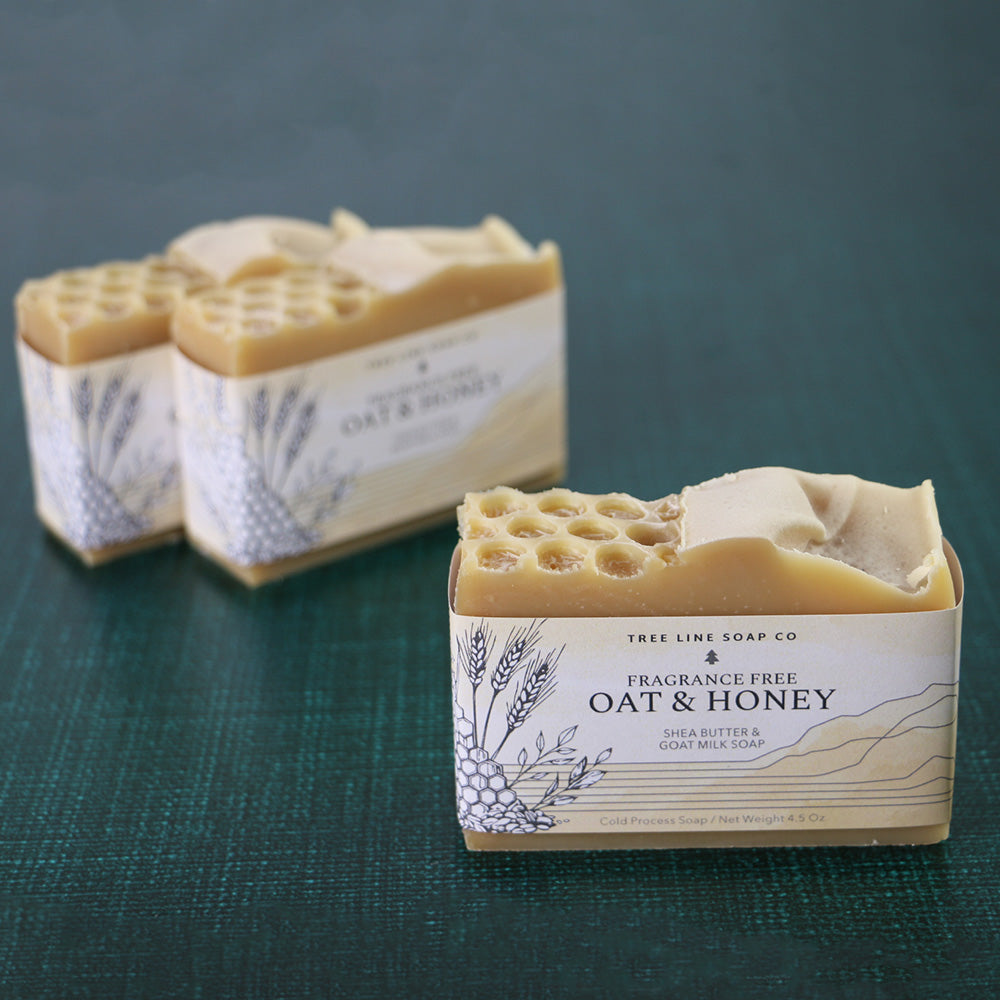 One bar of Oat & Honey soap stands in front of two other bars of the same fragrance.