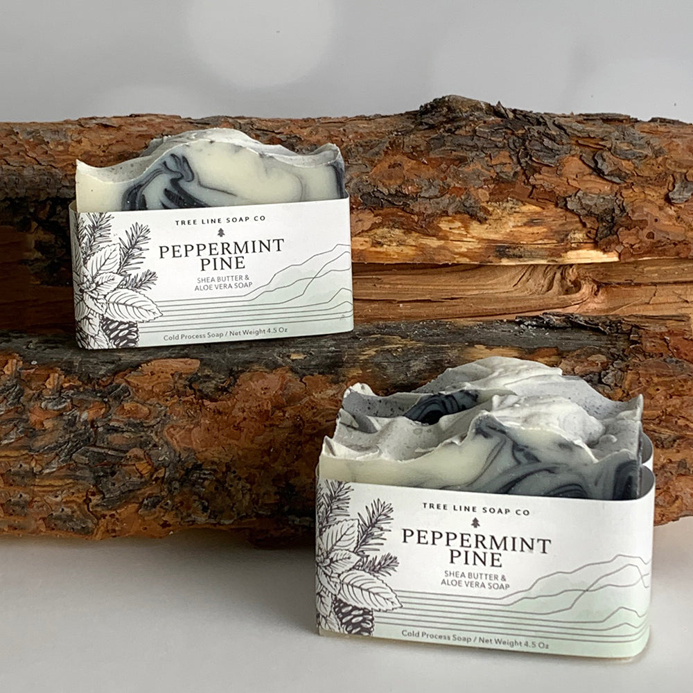 Three bars of Peppermint Pine soap sit side by side with the bark of wood logs as a background.