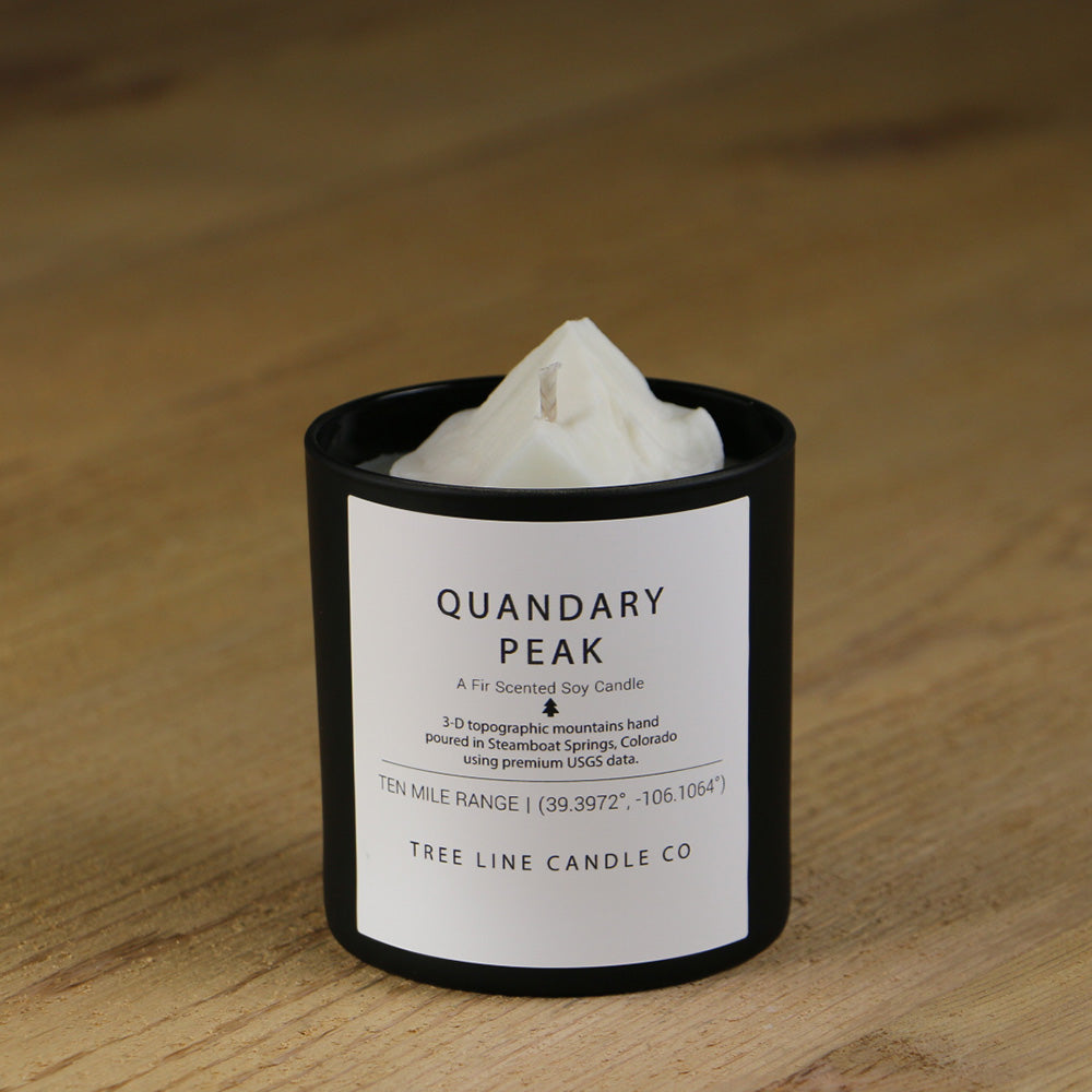 A white soy wax replica candle of Quandary Peak in a round, black glass.
