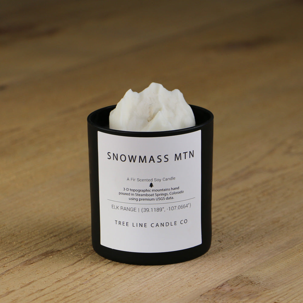 A white soy wax replica candle of Snowmass Mtn. in a round, black glass.