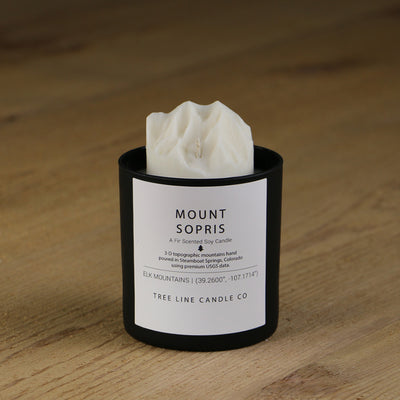 A white soy wax replica candle of Mount Sopris in a round, black glass.