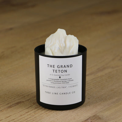  A white soy wax replica candle of The Grand Teton in a round, black glass.