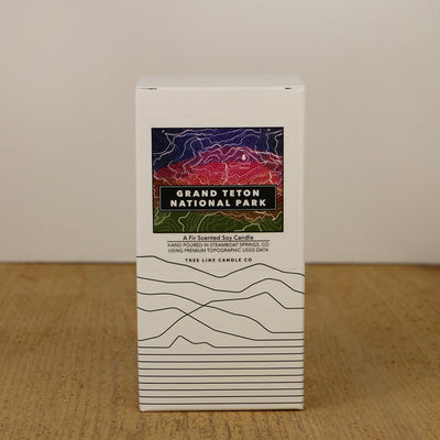 A white box with a purple, red and green label with topography lines by Tree Line Candle Co.