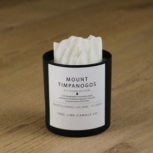 A white soy wax replica candle of Mount Timpanogos in a round, black glass.