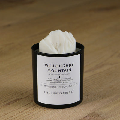 A white soy wax replica candle of Willoughby Mountain  in a round, black glass.