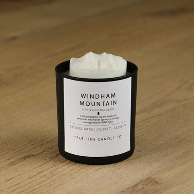 A white soy wax replica candle of Windham Mountain in a round, black glass.